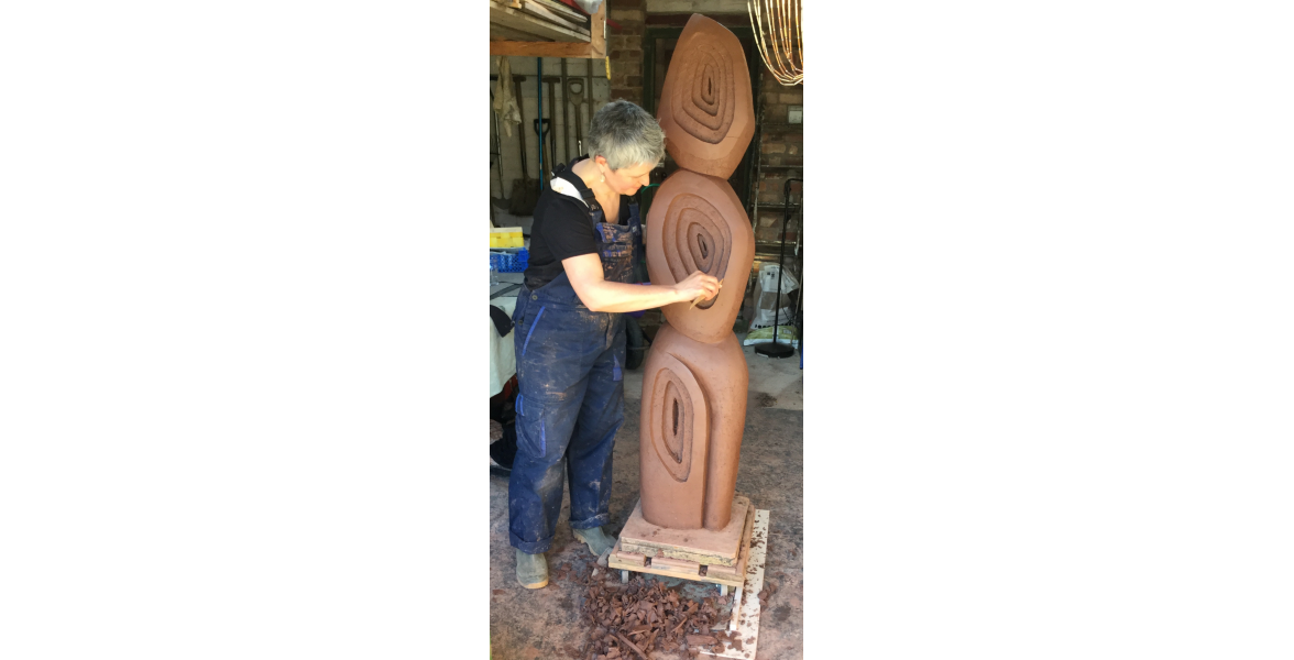 Carving garden sculpture in raw brick clay