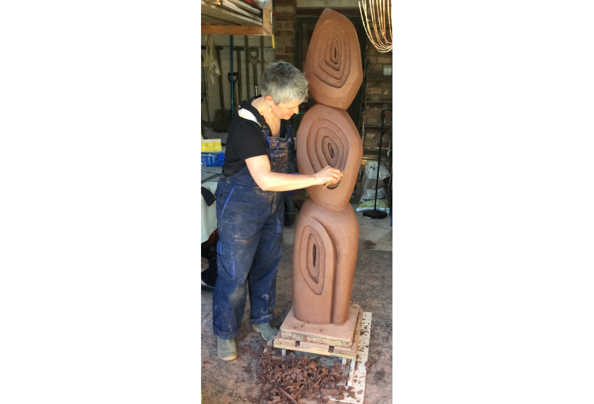 Carving garden sculpture in raw brick clay